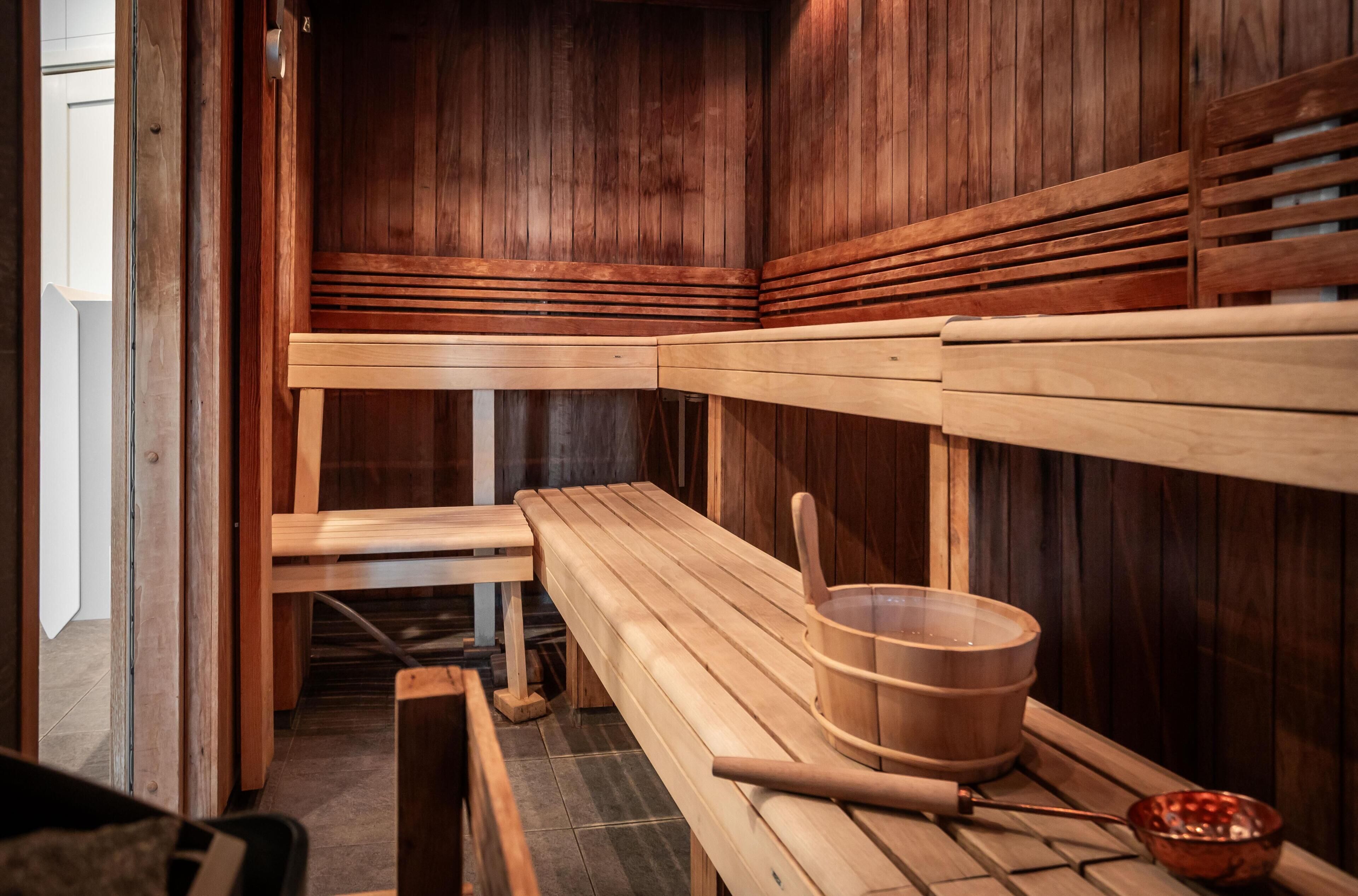 A sauna with wooden benches and a wooden bucket.