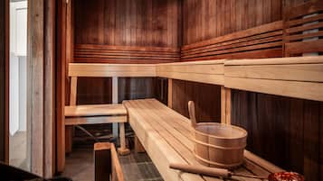 A sauna with wooden benches and a wooden bucket.