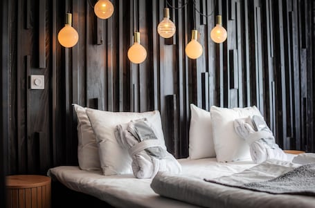 A bed with white bedding, a wooden wall, and hanging light fixtures.. Best Western Gustaf Fröding Hotel & Konferens
