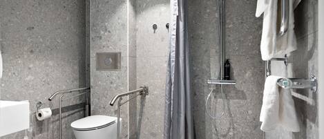 A modern bathroom with a shower, toilet, and handrails.