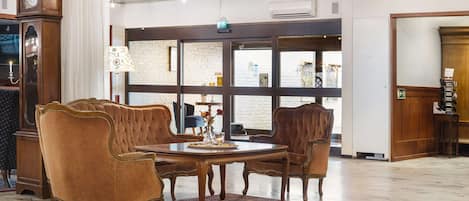 A lobby with a wooden table and chairs, a clock, and a large window.