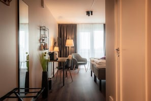 A compact hotel room with a bed, a desk with a chair, a small table, a mirror, a lamp, and a potted plant. - Best Western Gustaf Fröding Hotel & Konferens (Karlstad)