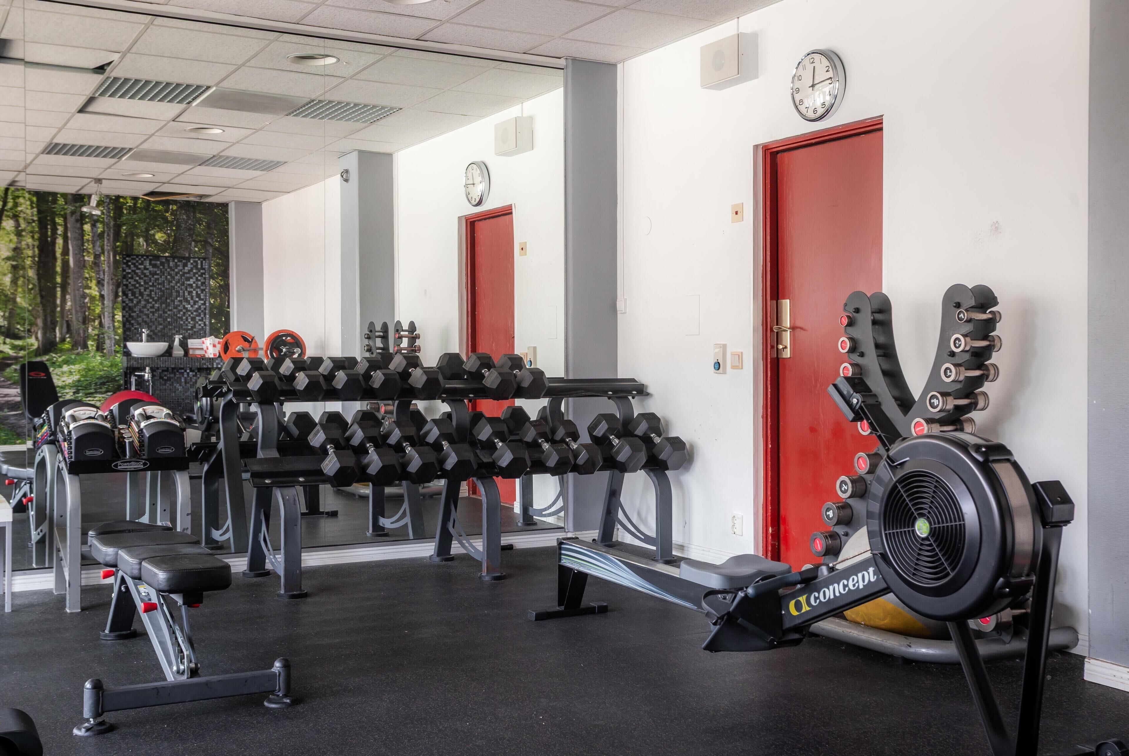 Une salle de sport équipée de divers appareils, notamment des haltères, un banc et un appareil de musculation.