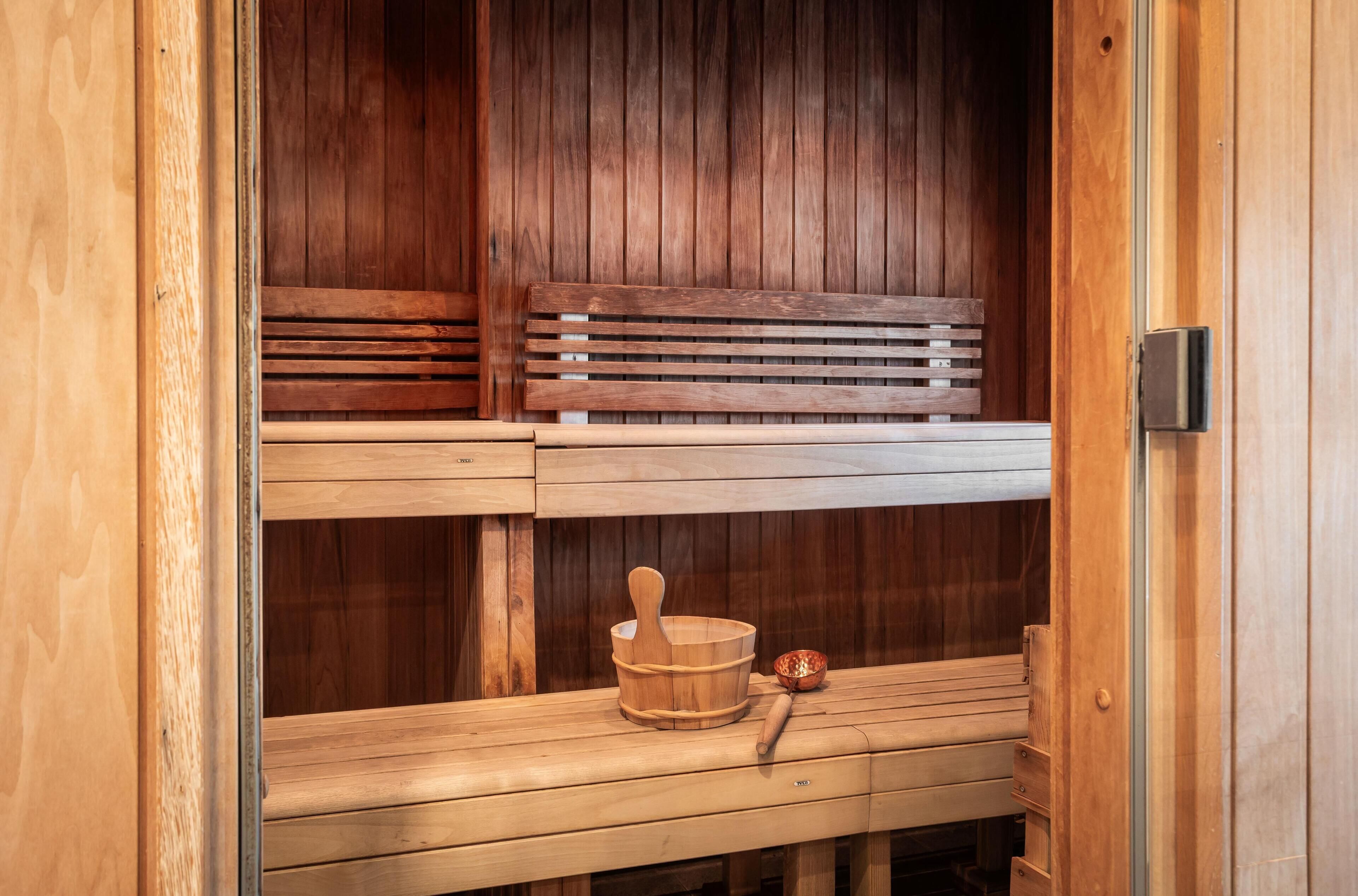 A wooden sauna with benches, a wooden bucket, and a wooden handle.