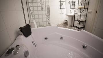 Ein modernes Badezimmer mit einer großen Badewanne, einer Toilette und einem Waschbecken. Es gibt eine Duschkabine aus Glas sowie einen Handtuchhalter mit Handtüchern.
