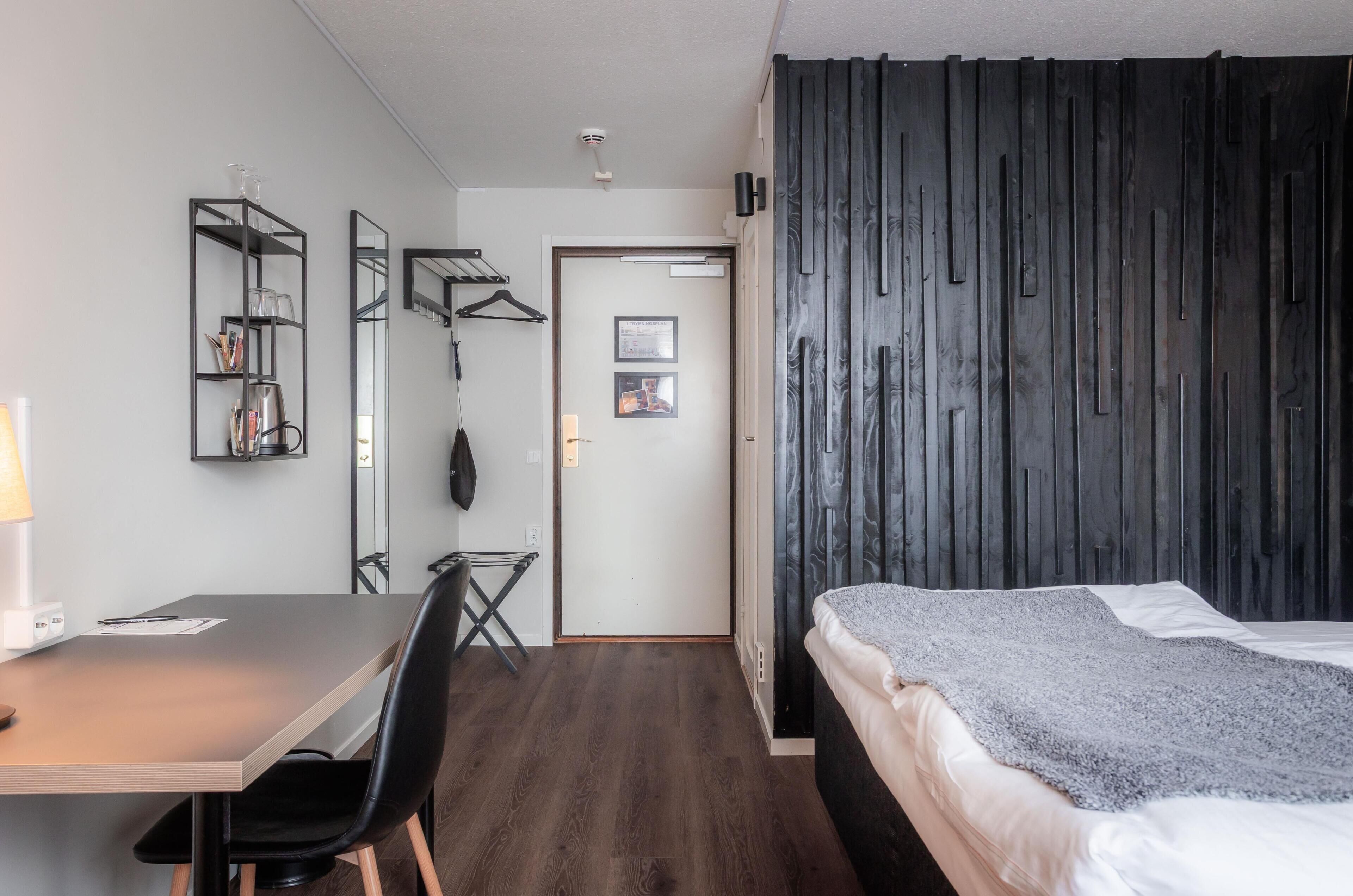 A room with a bed, a desk, a chair, a wardrobe, and a mirror.