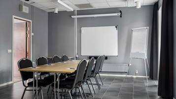 Une salle de conférence équipée d’une longue table, de six chaises, d’un tableau blanc et d’un chevalet pour paperboard.