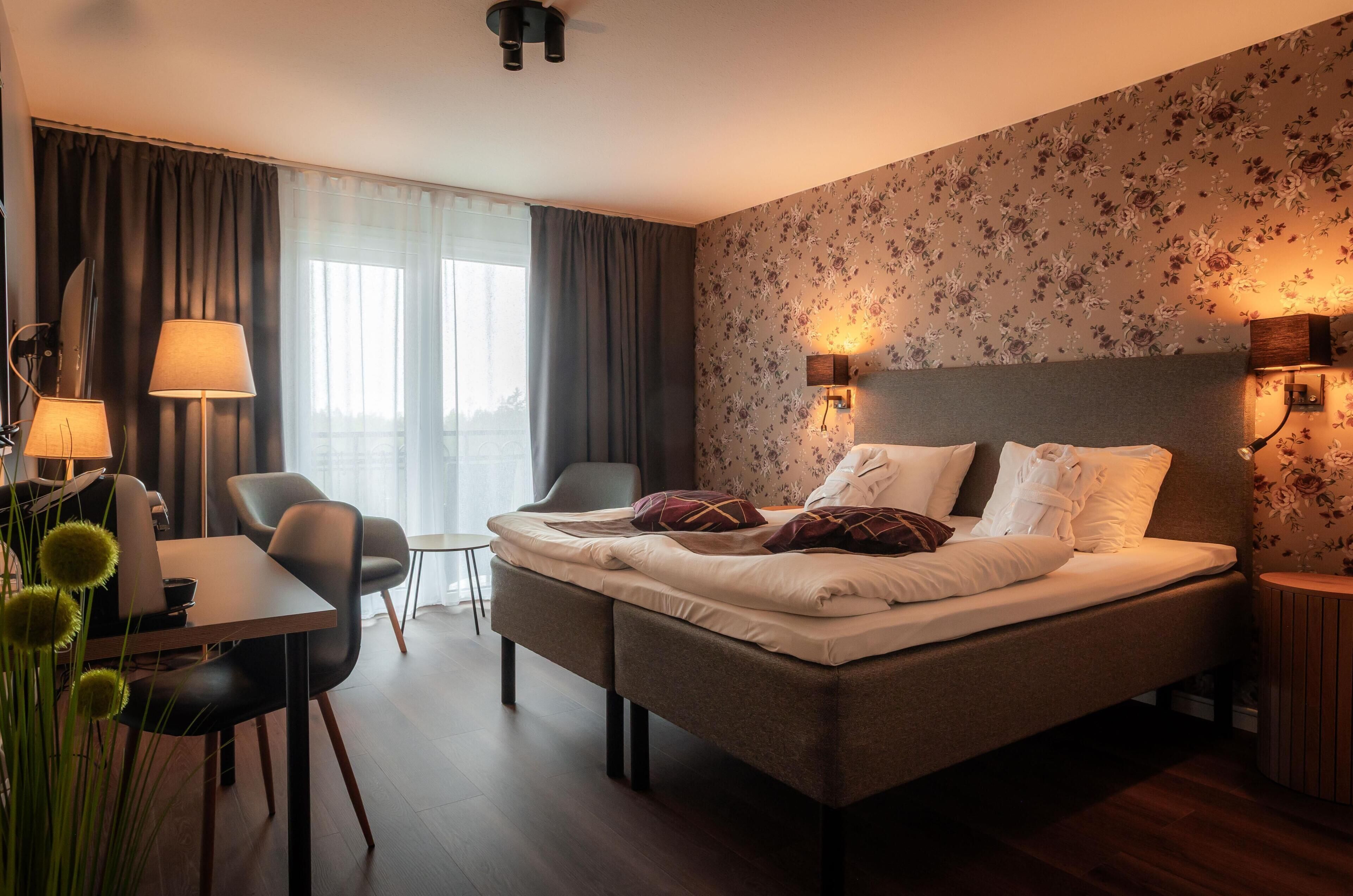 A hotel room with a bed, bedside lamps, a desk, and a chair.
