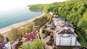 A coastal residential area with a large white building, a red-roofed house, and a beach. - Grand Hotel Binz (Binz)