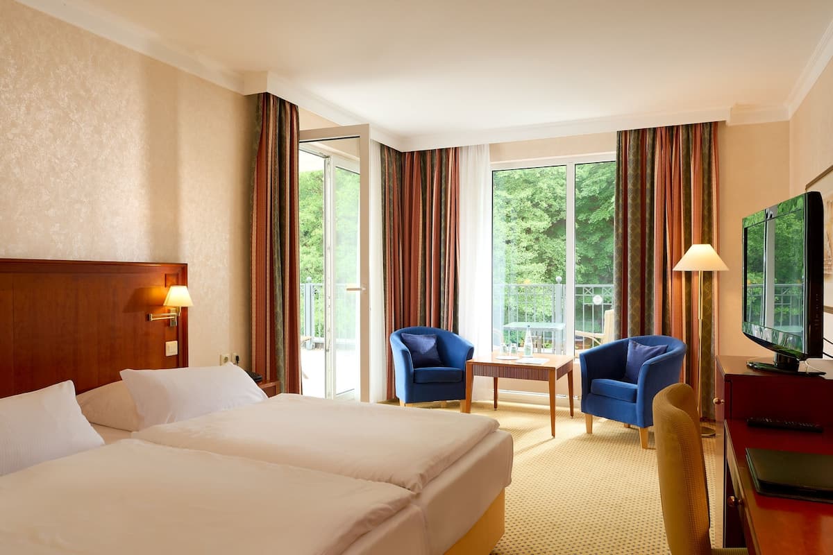 Une chambre d’hôtel avec deux lits, une télévision, un bureau et une chaise.