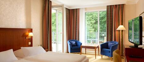 A hotel room with two beds, a TV, a desk, and a chair.