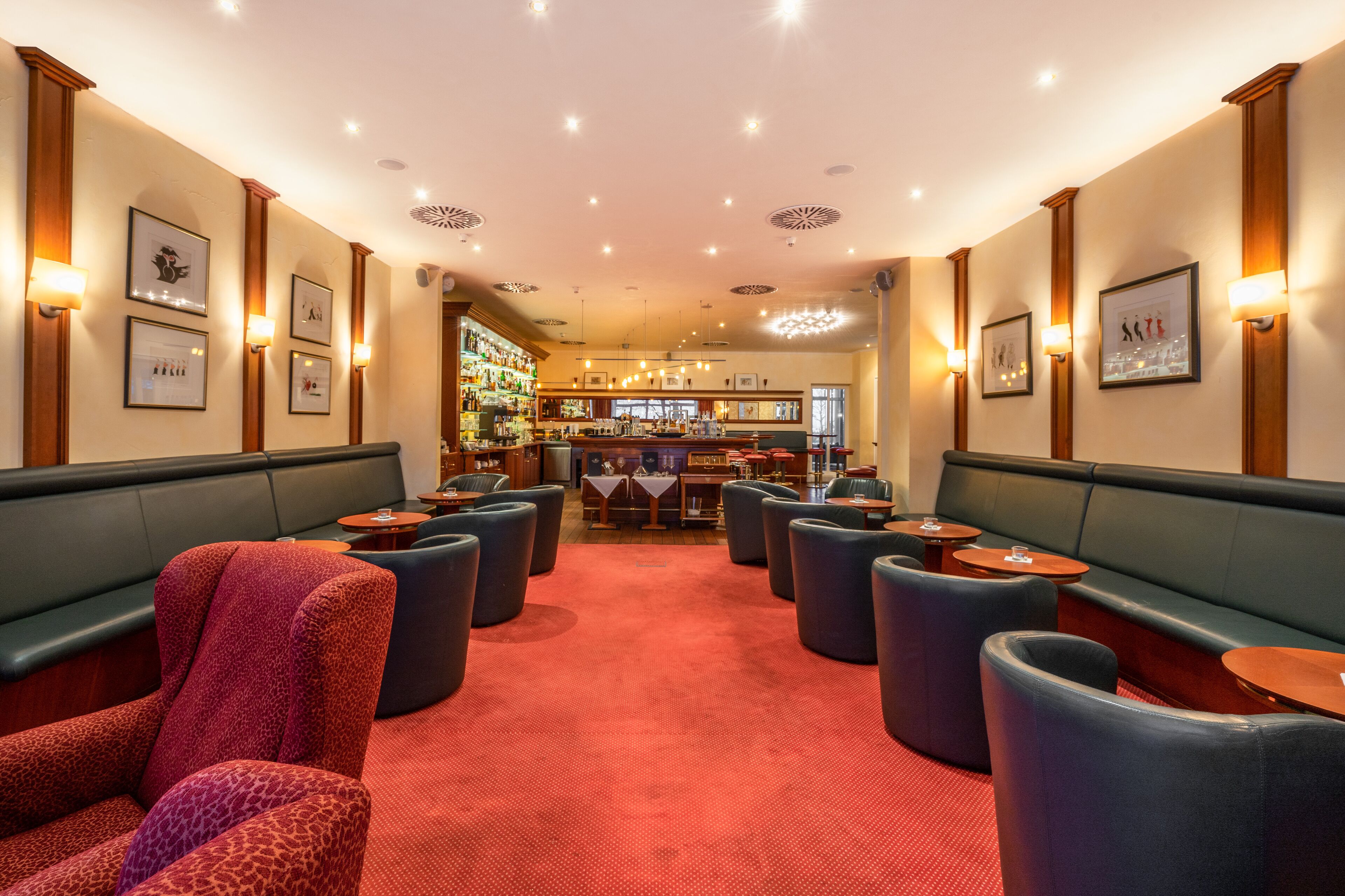 Eine Hotelhalle mit Sitzbereichen, einer Bar und gerahmten Bildern an den Wänden.