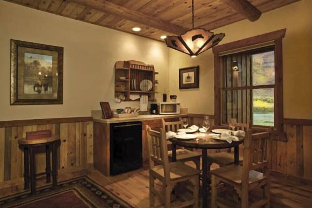 A dining area with wooden furniture, a chandelier, and a view through a window.