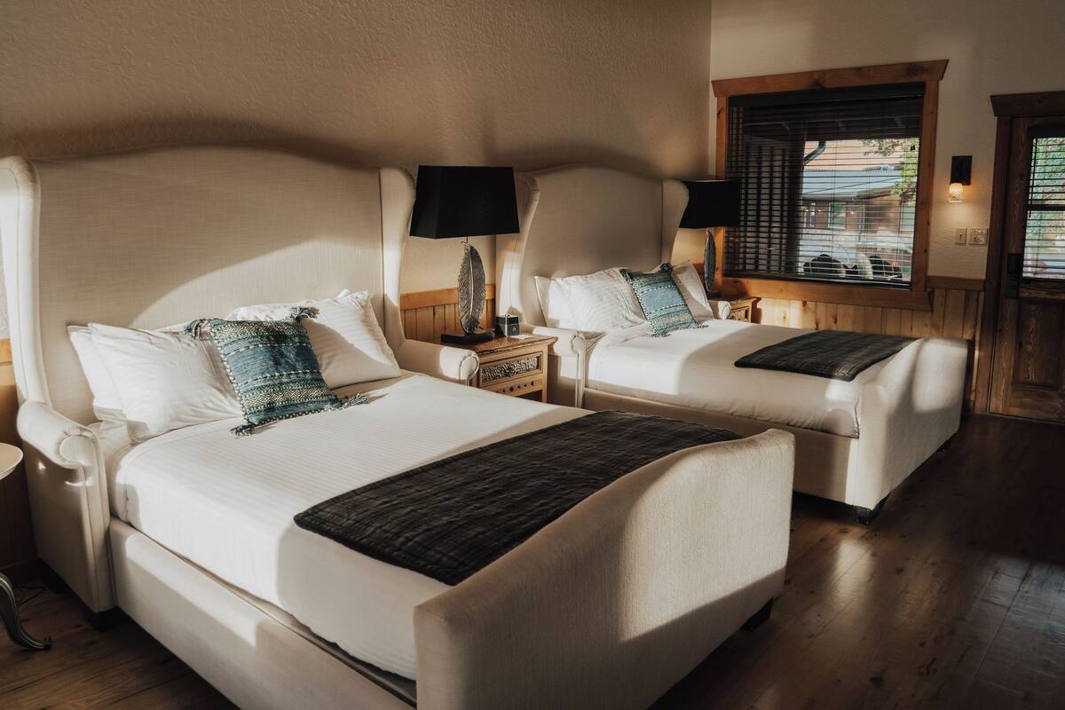 A double room with two beds, each with a nightstand, lamp, and decorative items.