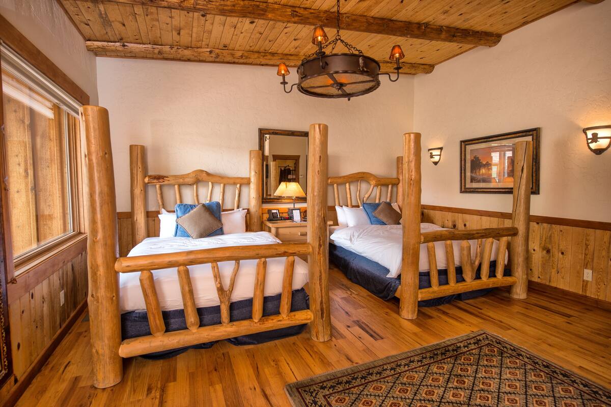 A rustic room with wooden beds, a chandelier, and a patterned rug.