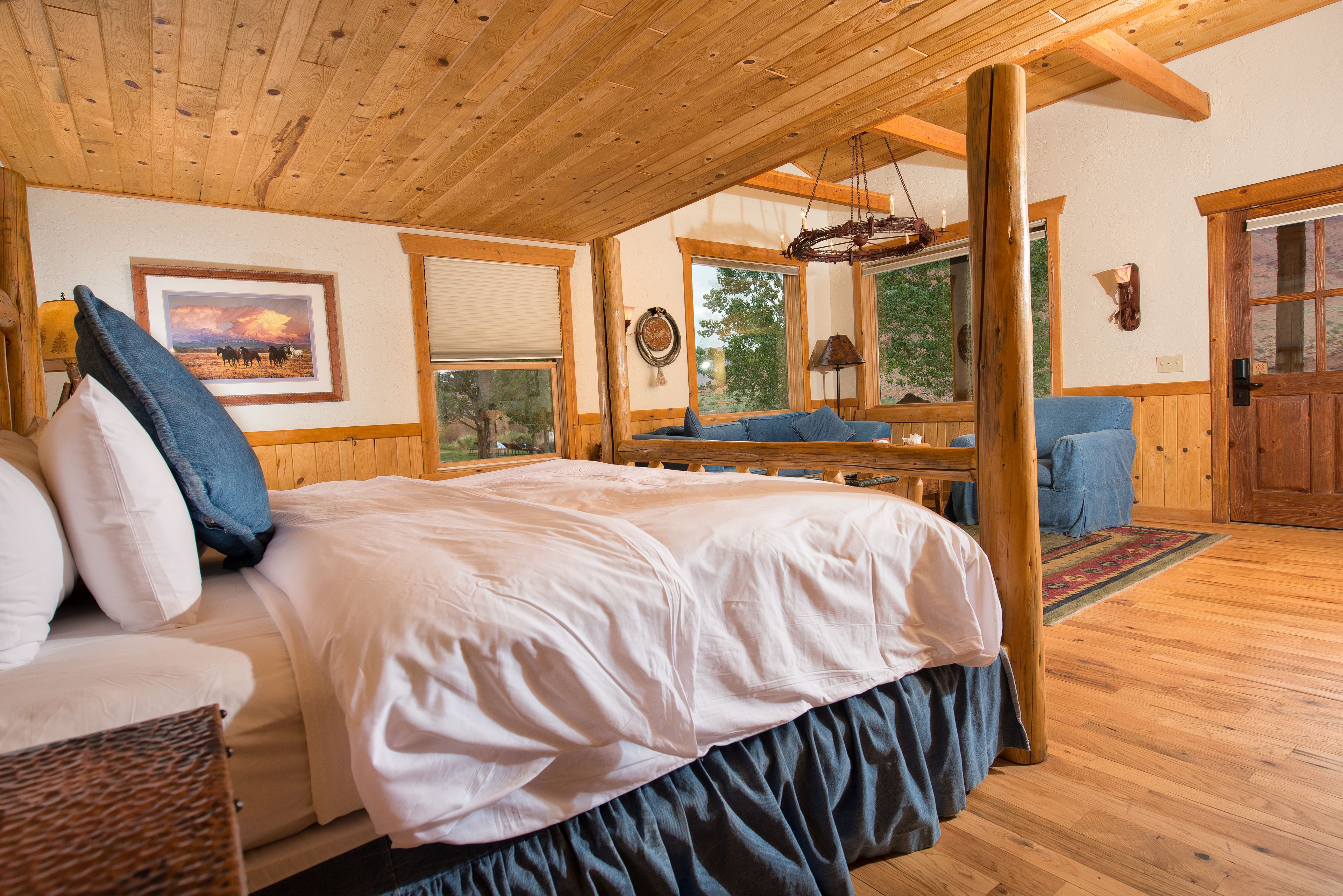 A wooden cabin bedroom with a bed, a chair, a table, and a window.
