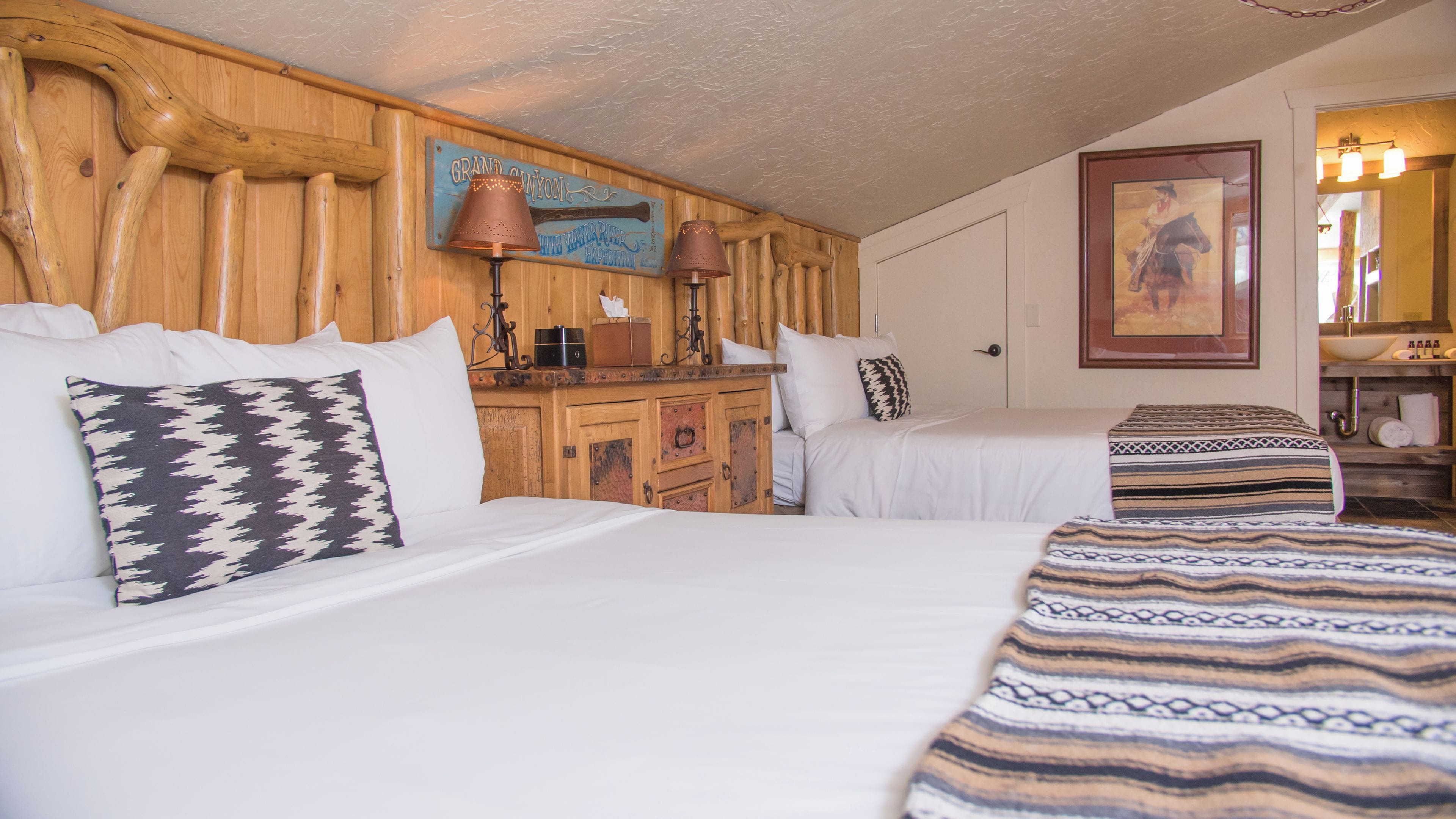 A hotel room with two beds, wooden headboard, a wooden dresser, a lamp, and a painting on the wall.