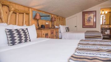 A hotel room with two beds, wooden headboard, a wooden dresser, a lamp, and a painting on the wall.