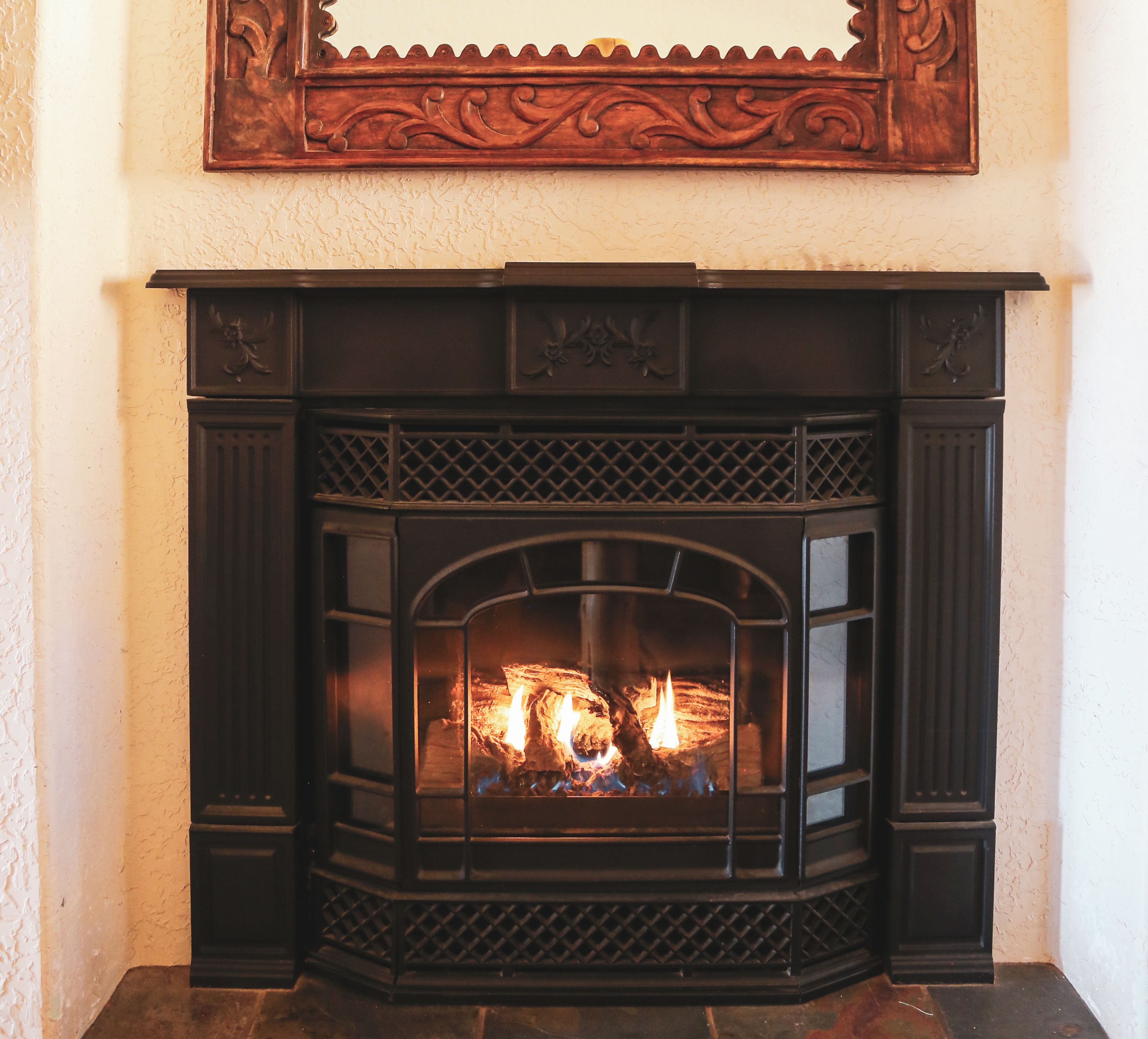 Una chimenea con un faldón decorativo y fuego encendido.
