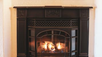 Una chimenea con un faldón decorativo y fuego encendido.
