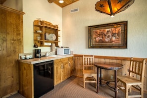 A kitchen with wooden cabinets, a microwave, a coffee maker, and a dining table with chairs.