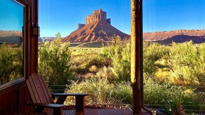 A wooden deck with a table and chairs, overlooking a mountainous landscape.