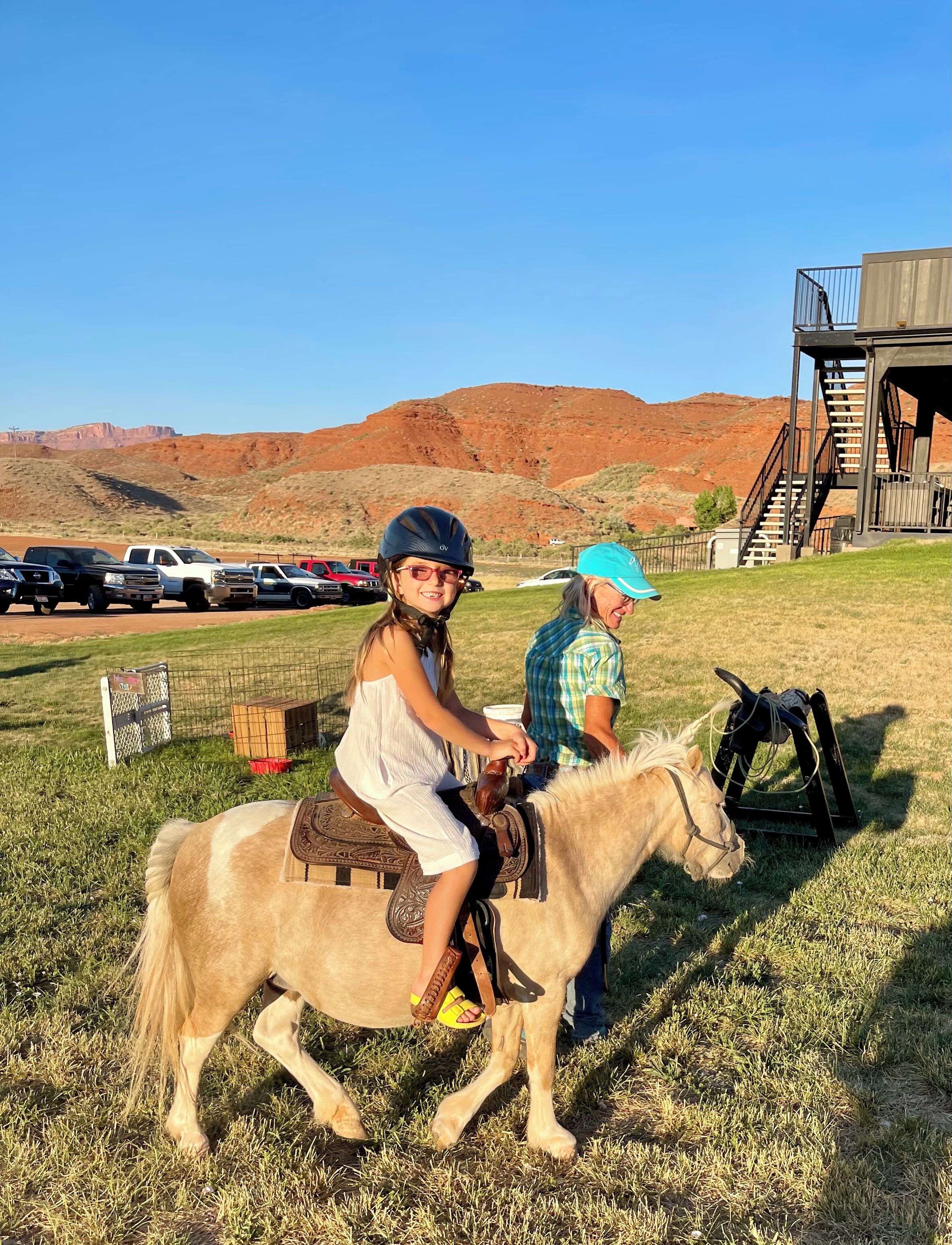 A person riding a horse in a grassy field with a mountainous backdrop.