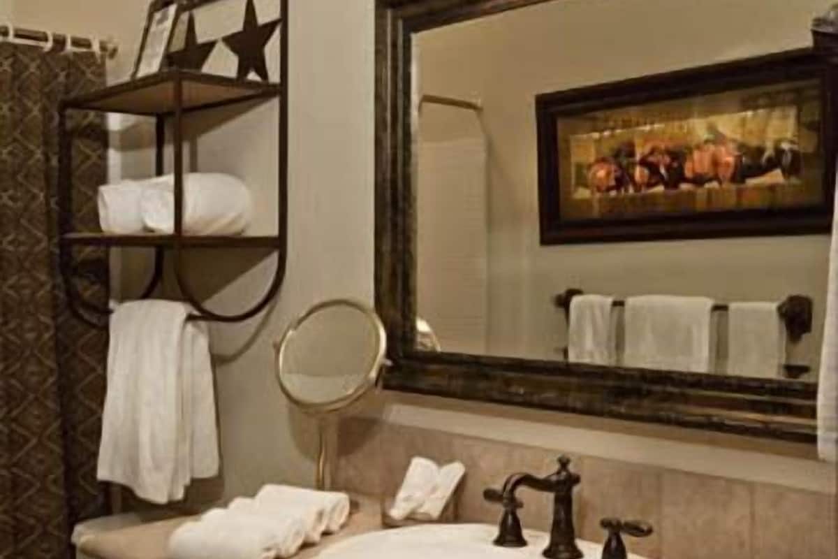 A bathroom with a large mirror, a sink, and a towel rack.