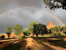 Un parque con un sendero de tierra, árboles y una gran formación rocosa.