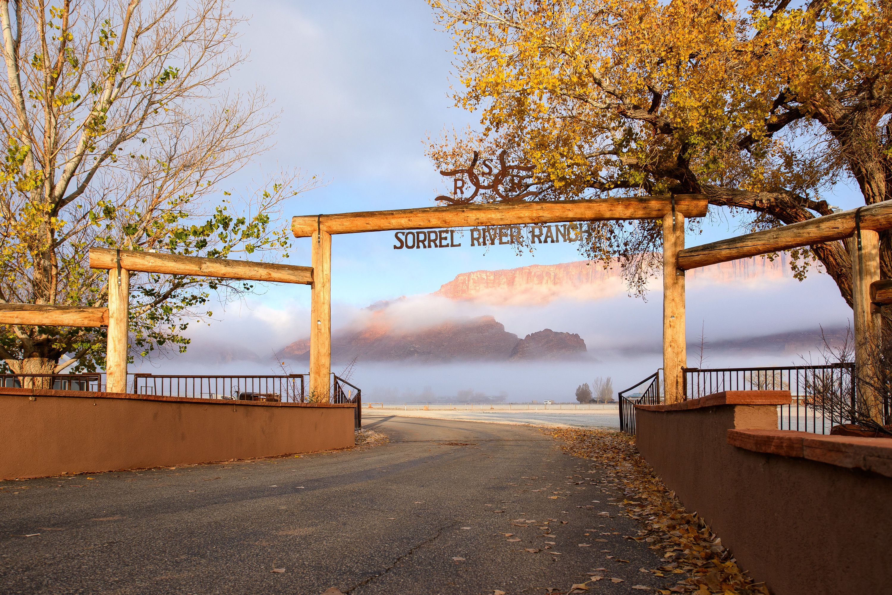 Un arc en bois portant l’inscription « SORREL RIVER RANCH » marque l’entrée d’un chemin qui offre une vue sur les montagnes et une rivière.