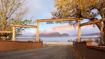 Un arc en bois portant l’inscription « SORREL RIVER RANCH » marque l’entrée d’un chemin qui offre une vue sur les montagnes et une rivière.