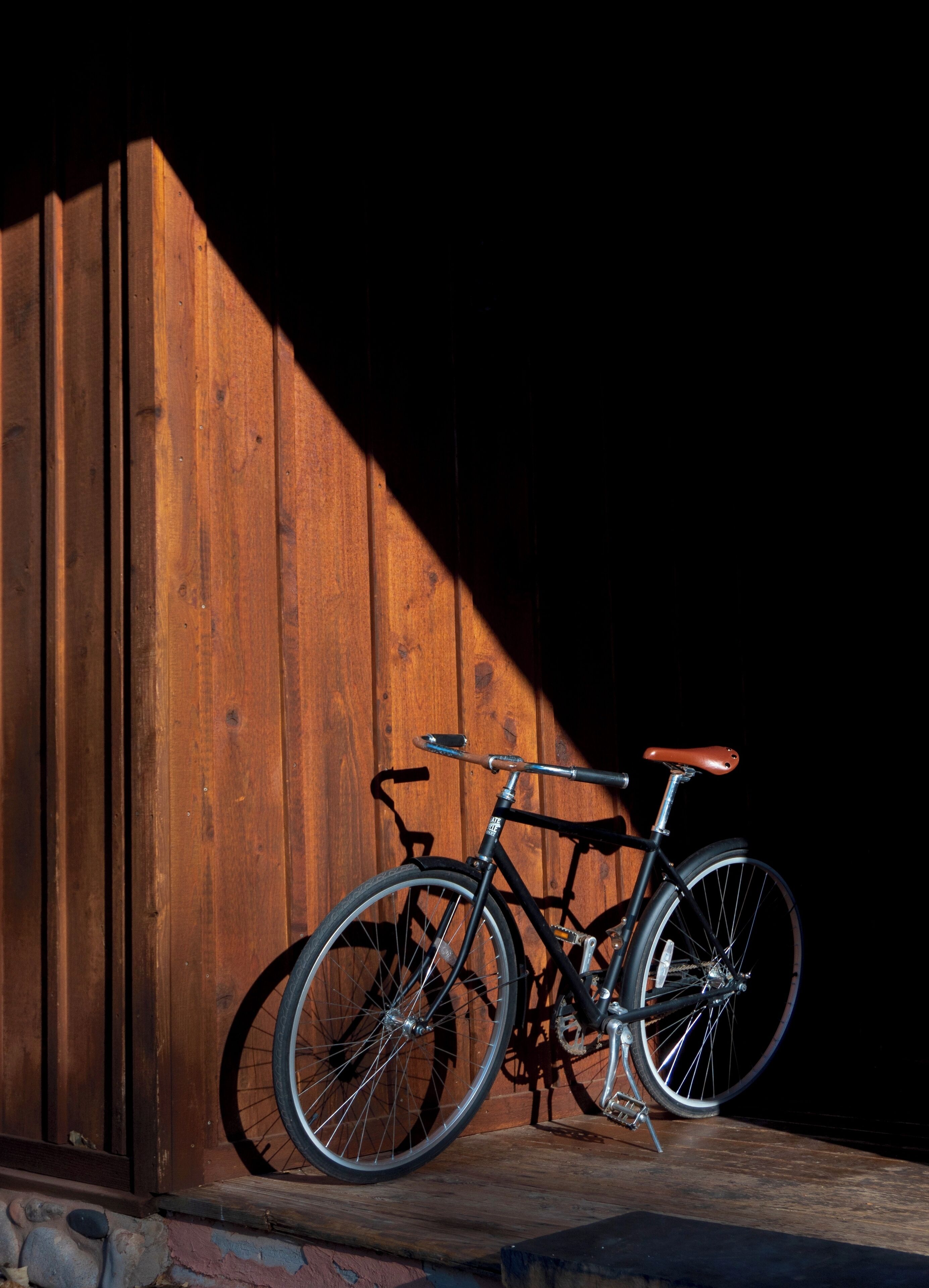 A bicycle leaning against a wooden wall with a sloped roof.