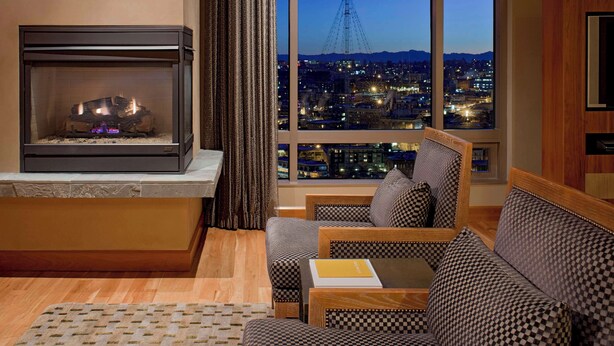 A modern living room with a fireplace, large windows with a city view, and comfortable seating. - Grand Hyatt Seattle (Seattle)