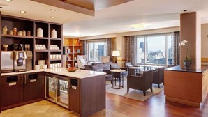 A modern hotel room with a kitchen area, dining space, and a seating area with a city view. - Grand Hyatt Seattle (Seattle)