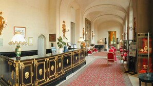 A grand lobby with a long reception desk, red carpet, and classical architecture. - Château d'Artigny (Montbazon)