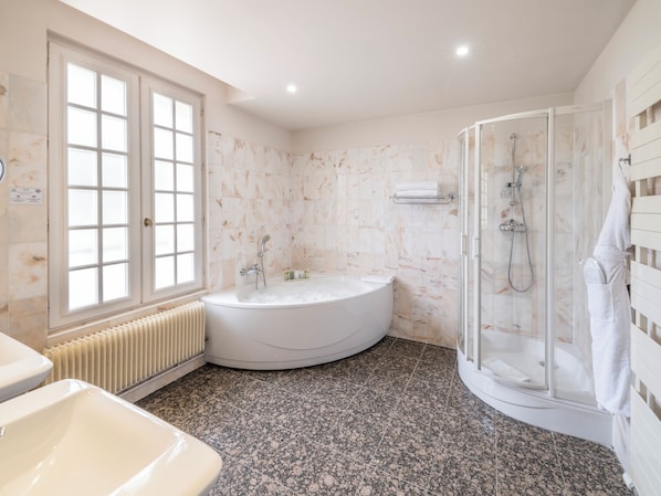 A modern bathroom with a freestanding bathtub, a glass-enclosed shower, and a window with frosted glass.
