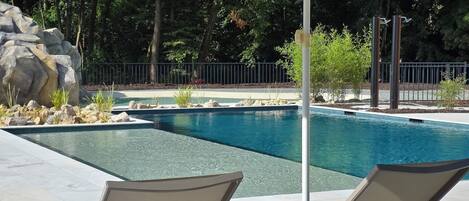 A poolside area with two lounge chairs and a large umbrella.