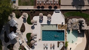 An aerial view of a resort with a central swimming pool, sun loungers, and a landscaped garden area. - Château d'Artigny (Montbazon)