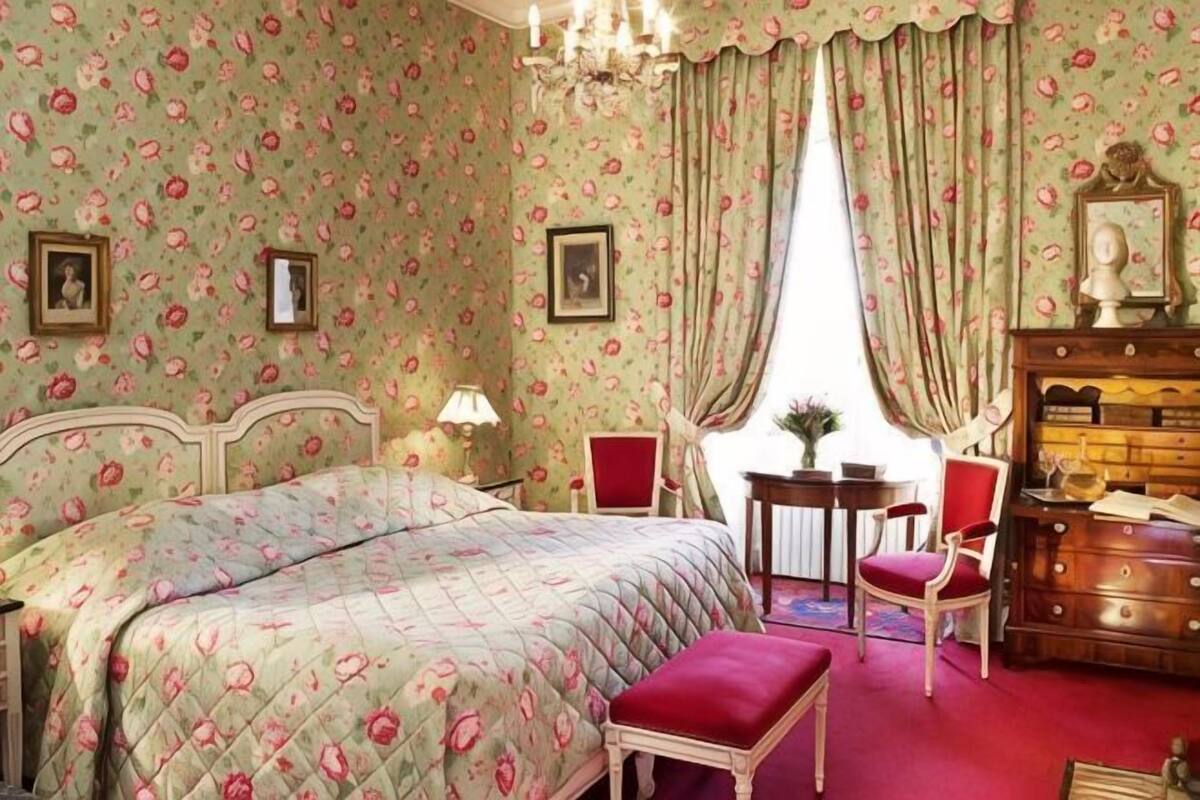 A bedroom with a bed, a chair, a dresser, and a table.