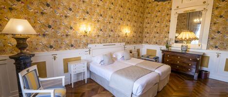 A bedroom with a double bed, a nightstand, a chair, a dresser, and a mirror.