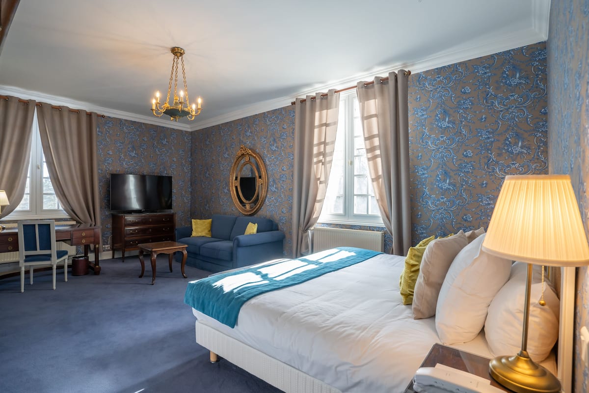 Ein Hotelzimmer mit einem großen Bett, einem Fernseher, einer Couch und einem Schreibtisch.