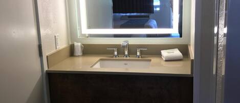 A bathroom with a large mirror, a sink, and a towel rack.
