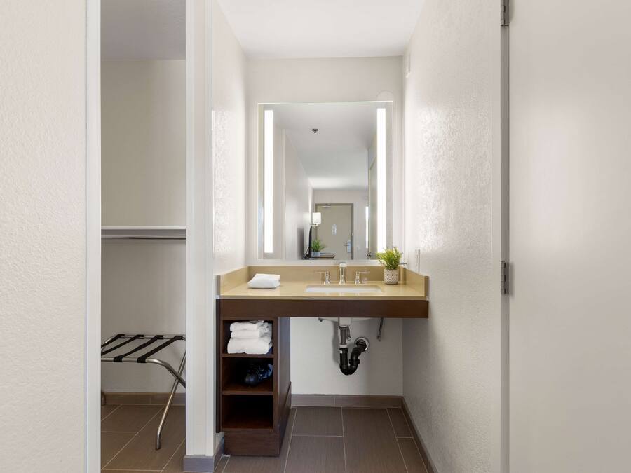 A modern bathroom with a built-in sink, a towel rack, and a mirror with integrated lighting.