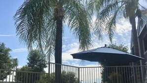 A patio area with a palm tree, outdoor seating, and a view of the street. - Good Nite Inn Redlands (Redlands)