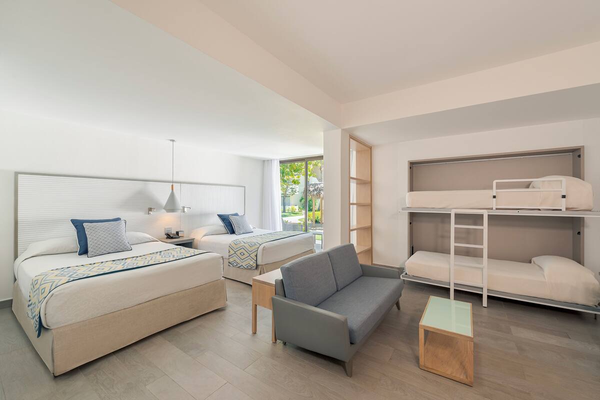 Ein modernes, helles Schlafzimmer mit einem großen Bett, einem Schlafsofa, einem Etagenbett und einem kleinen Tisch.