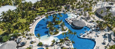 Una piscina al aire libre, sombrillas, sillones reclinables de piscina