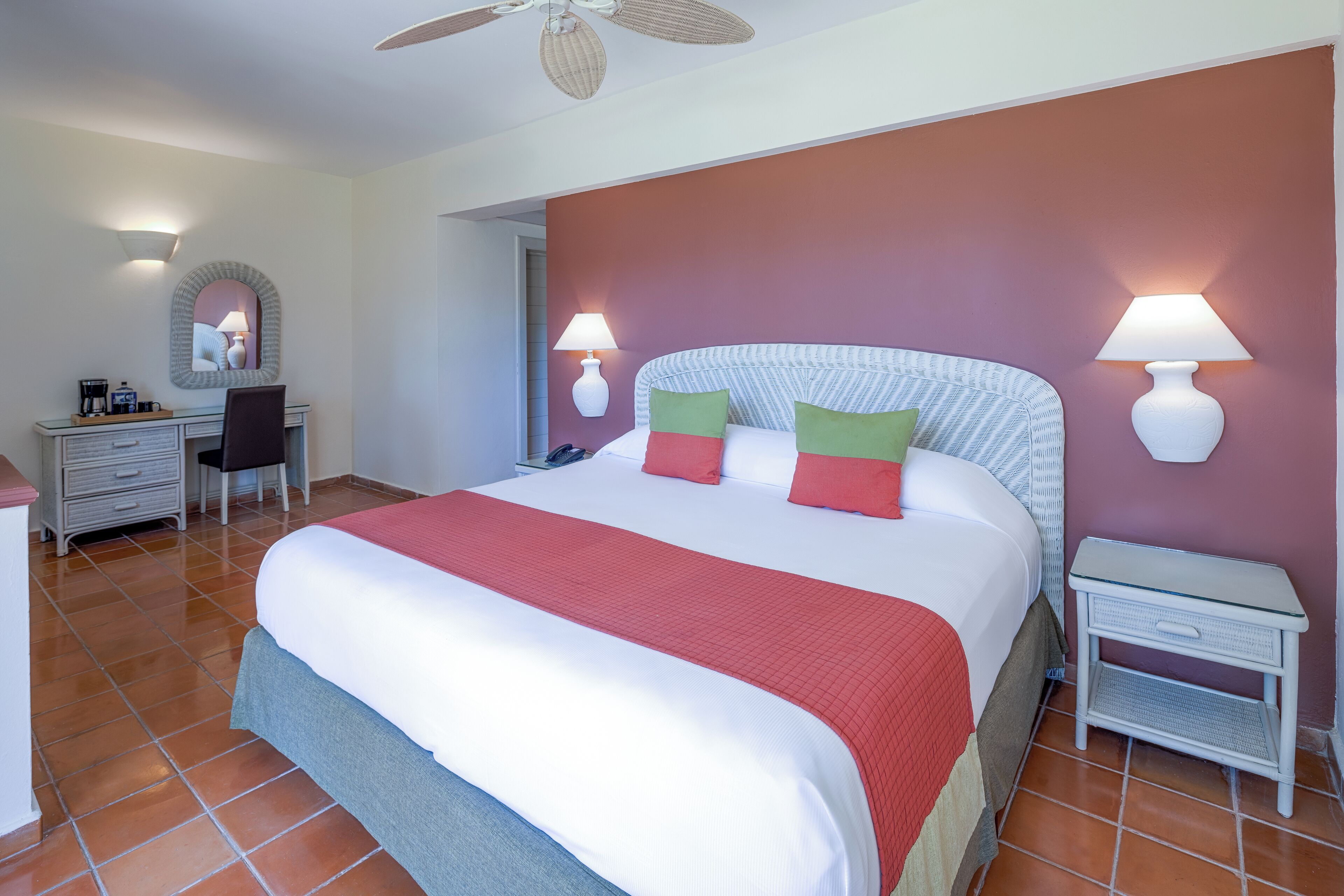 Habitación de hotel con una cama grande, dos lámparas de noche, un escritorio con silla y una mesita.