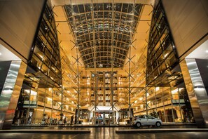 A modern building with a glass facade, a central atrium, and a car parked in front. - Hilton Buenos Aires (Buenos Aires)