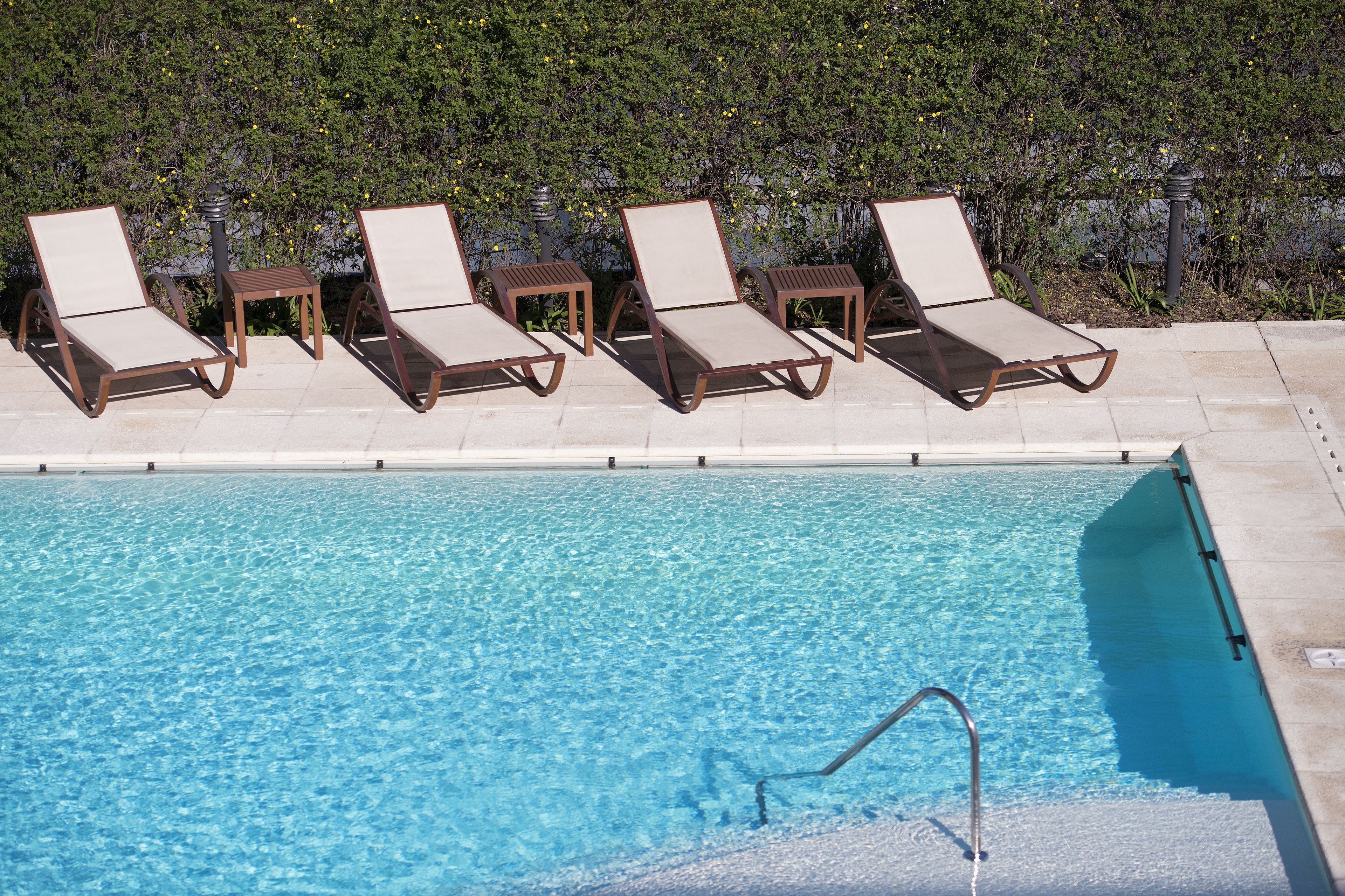 A poolside area with lounge chairs and a clear pool.