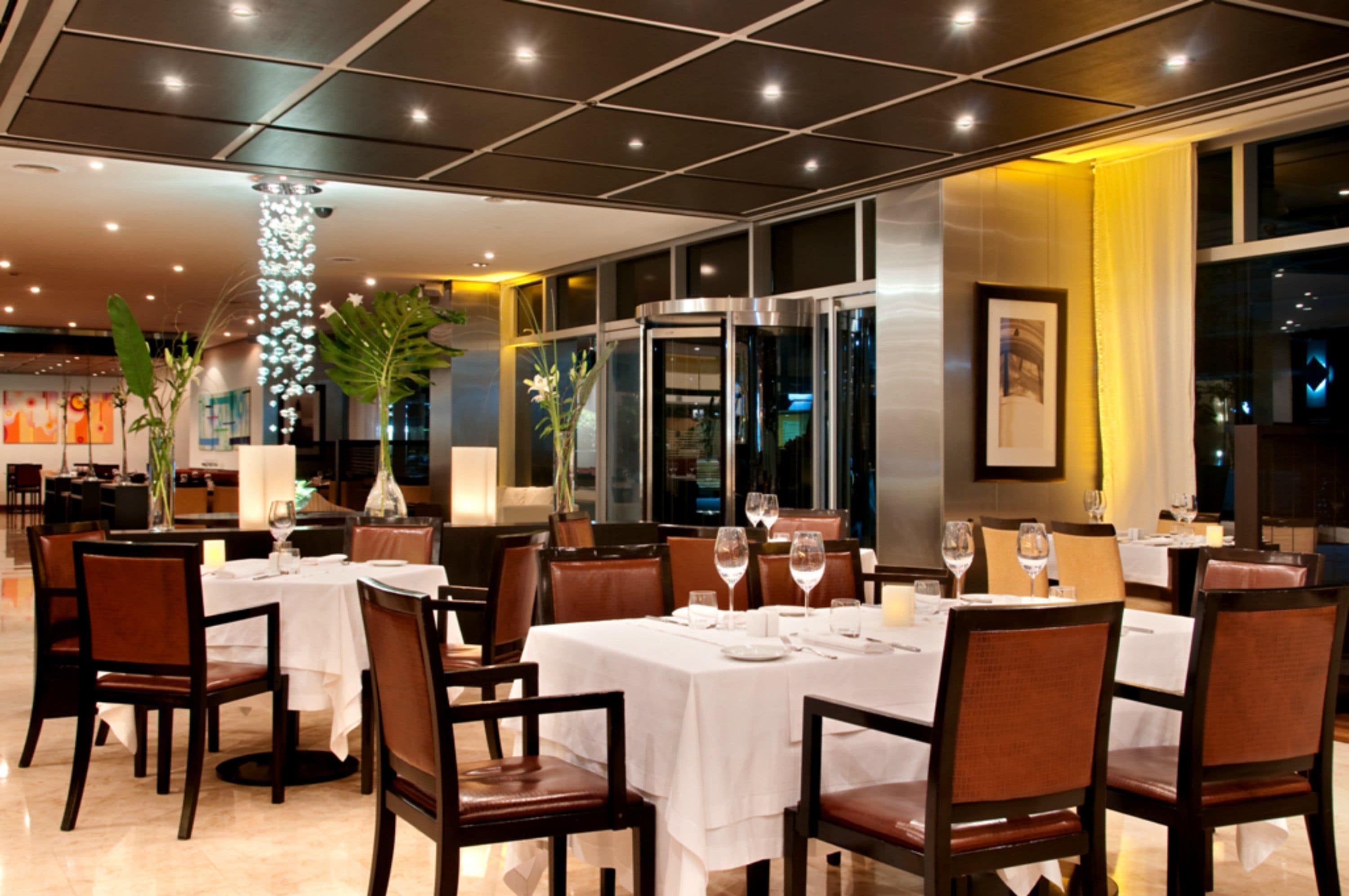 A restaurant with tables set for dining, chairs, and a decorative pillar.